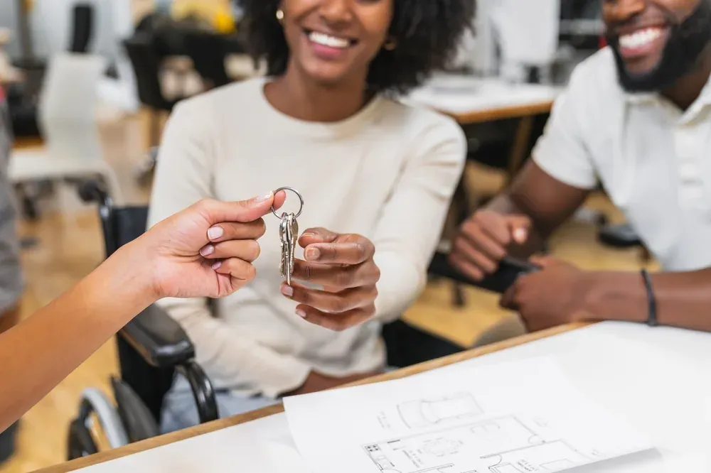 Keys being handed over to a couple of buyers, with the apartment floor plan on the table
